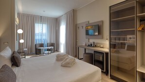 Une chambre d’hôtel avec un grand lit, un bureau, une chaise, une télévision et une armoire.