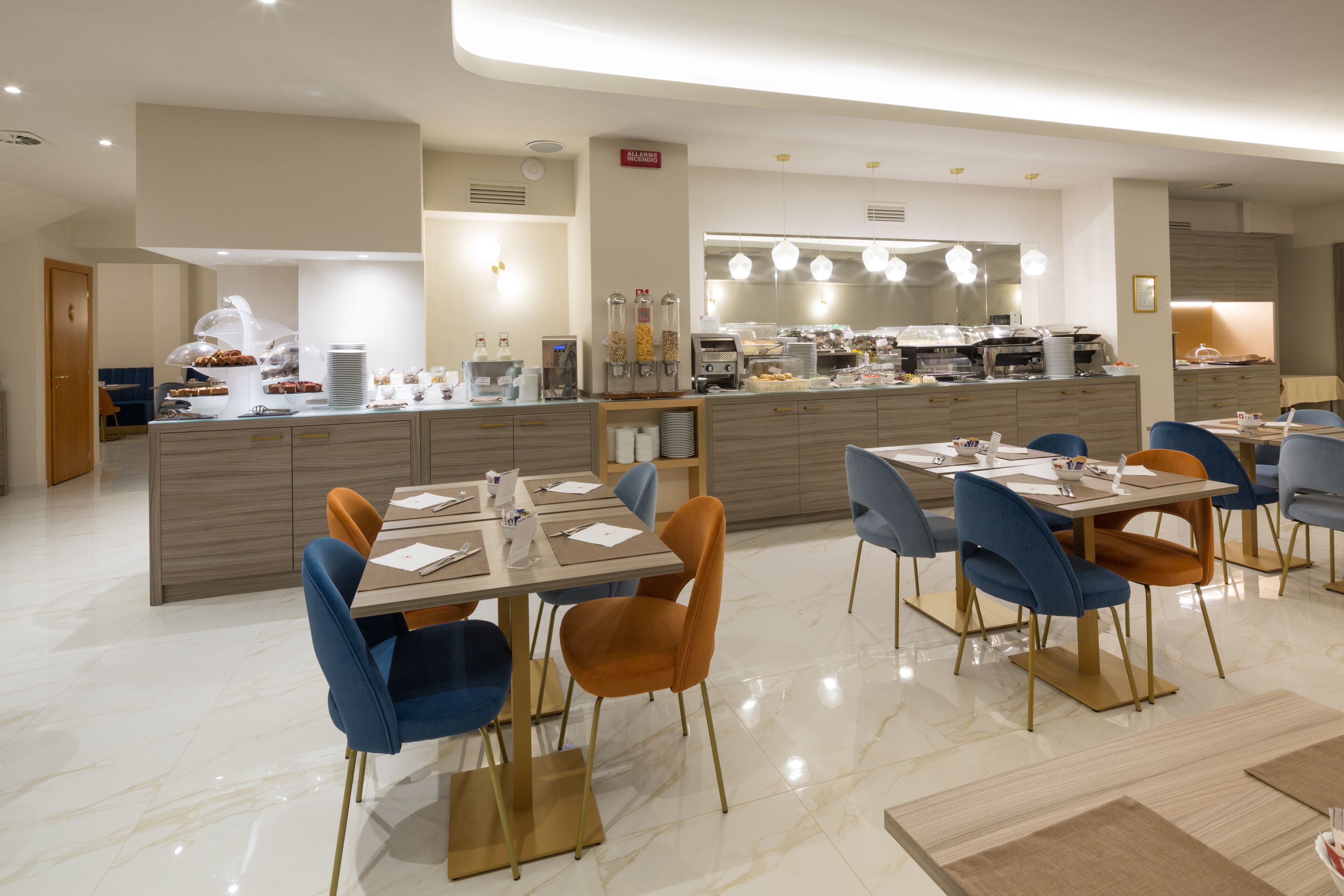 Ein moderner Essbereich mit einer zentralen Kochinsel, blauen und orangefarbenen Stühlen und einem Buffet.