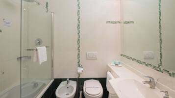 Een badkamer met een glazen douchecabine, een bidet, een toilet en een wastafel met spiegel erboven.