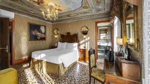 Ein luxuriöses Schlafzimmer mit einem großen Bett, einer verzierten Decke und einem Spiegel.
