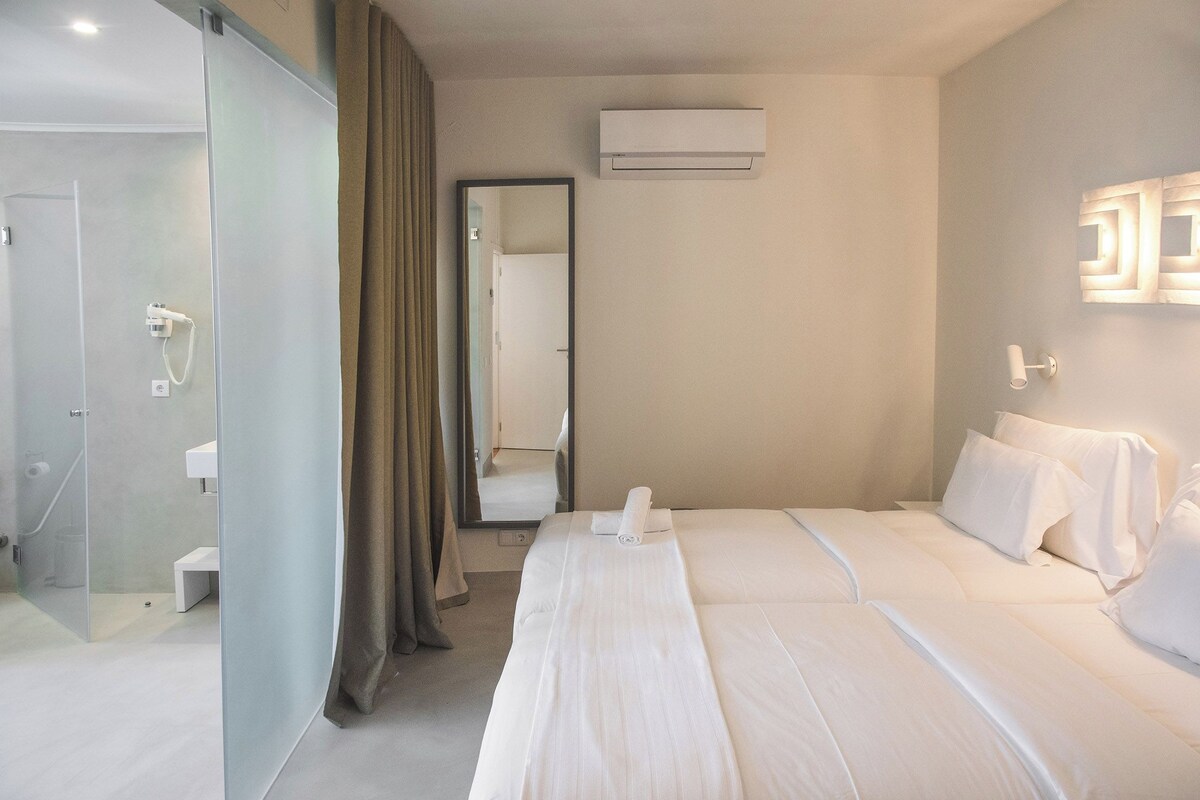 A hotel room with a bed, a bathroom, and a shower area.