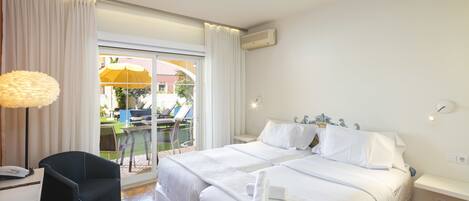 A hotel room with a bed, a desk, a chair, and a view of the outdoor area.