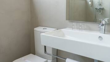 A modern bathroom with a toilet, sink, and shower.