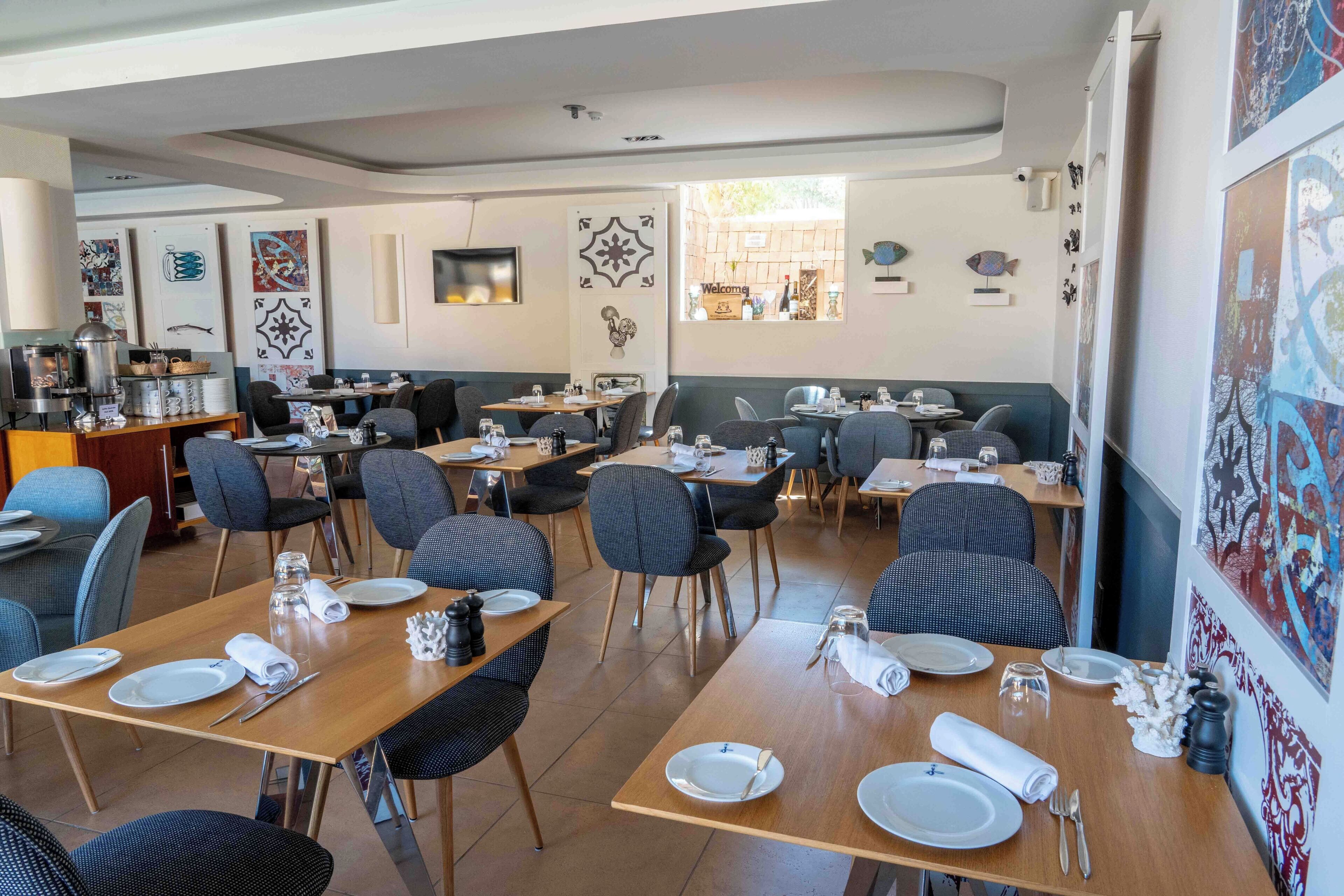 A restaurant with multiple tables and chairs, some with plates and cutlery set.