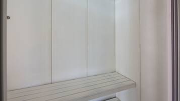 Um banheiro branco e minimalista, com um banco embutido e uma porta.