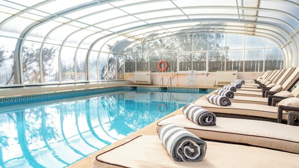 A pool area with lounge chairs and a glass-enclosed structure. - Costa D’Oiro Ambiance Village (Lagos)