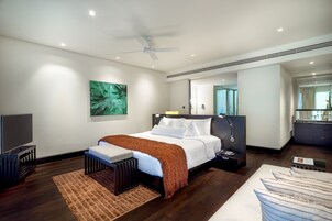 Una habitación de hotel moderna con una cama grande, un ventilador de techo, un televisor de pantalla plana y vistas a la ciudad desde la ventana.