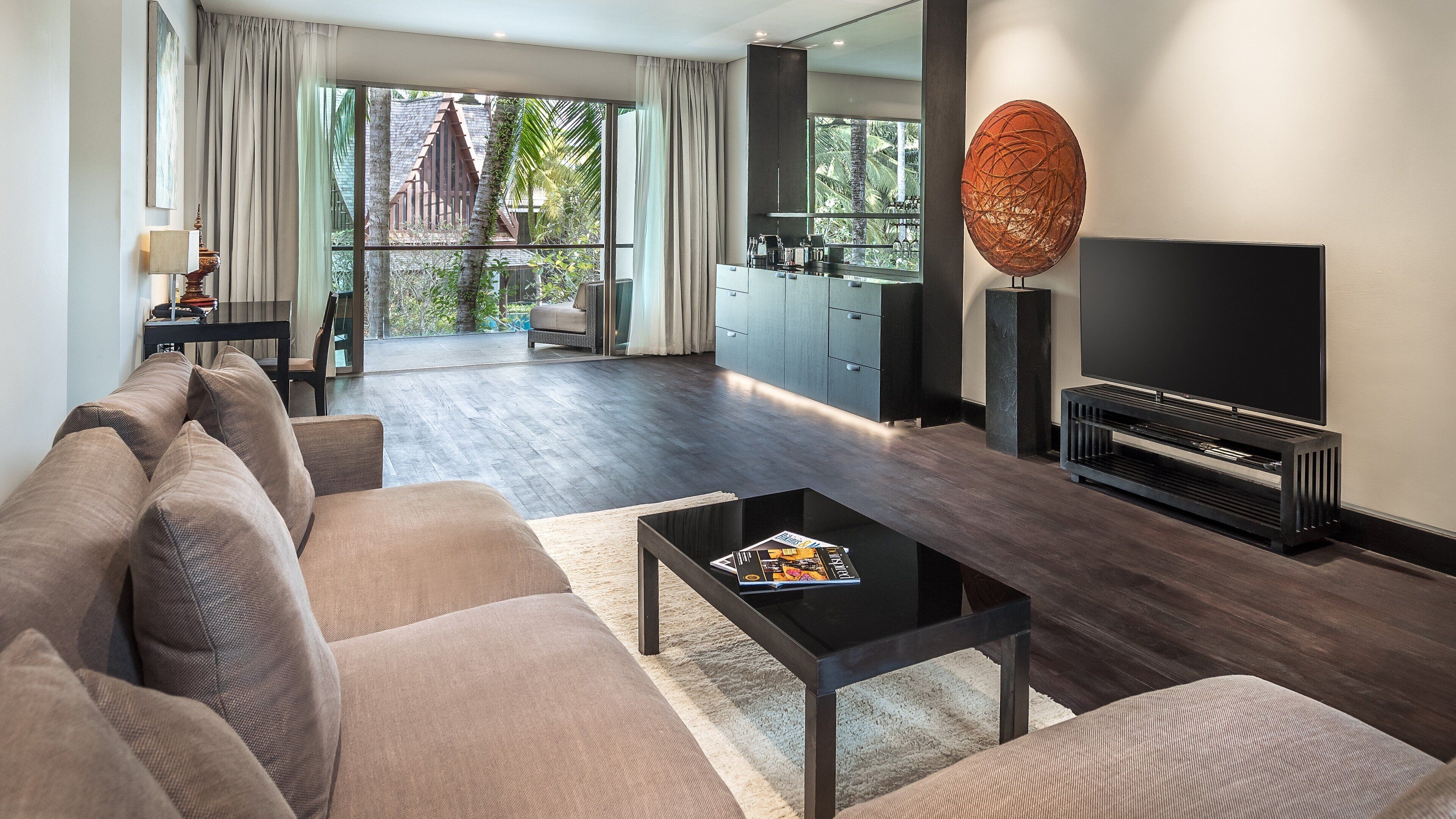 A modern living room with a sofa, coffee table, TV, and a large window with curtains.