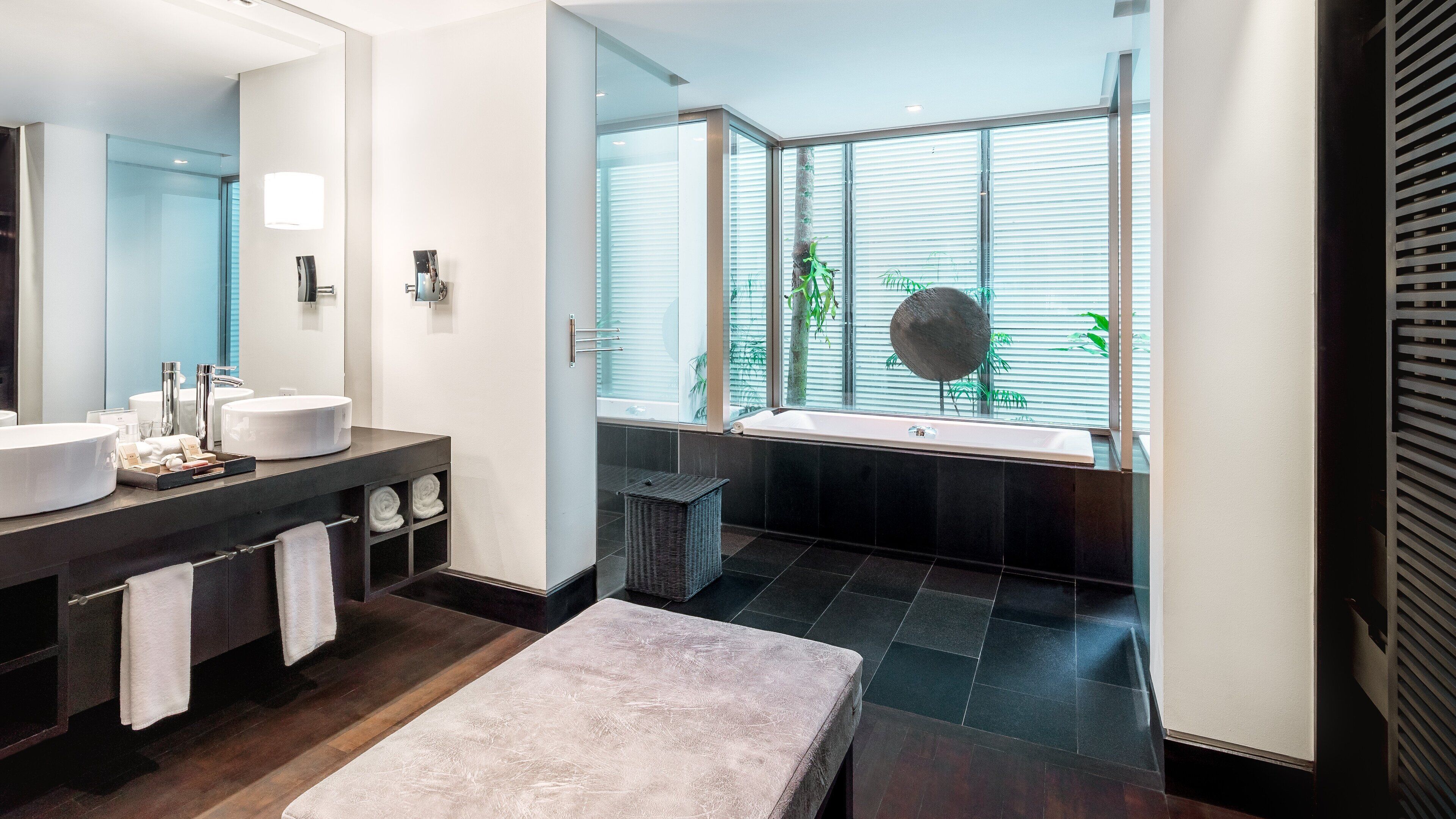 Un baño moderno con dos lavamanos, un espejo grande y una bañera.