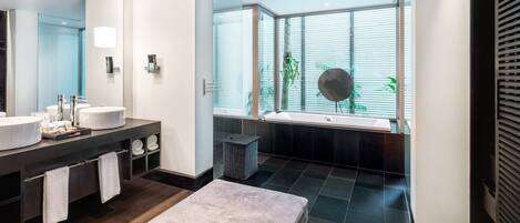 Un baño moderno con dos lavamanos, un espejo grande y una bañera.