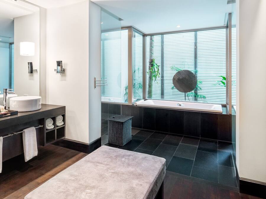 Un baño moderno con dos lavamanos, un espejo grande y una bañera.