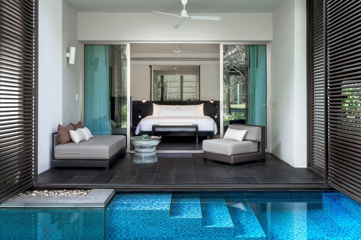Une chambre moderne avec un grand lit, deux canapés, une petite table et une piscine.