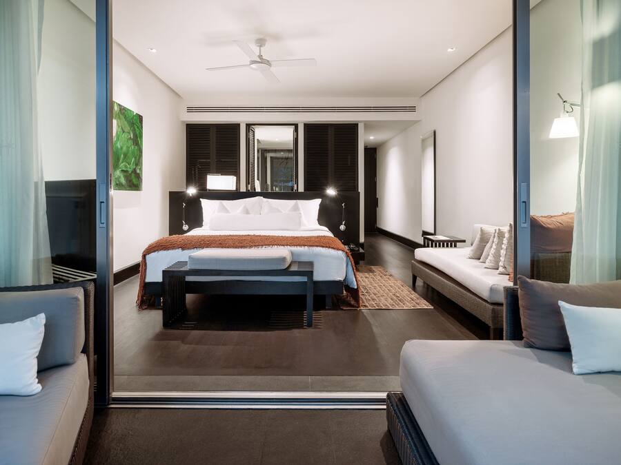 Ein modernes Hotelzimmer mit einem großen Bett, einer Couch, einem Schreibtisch und einem Sessel.