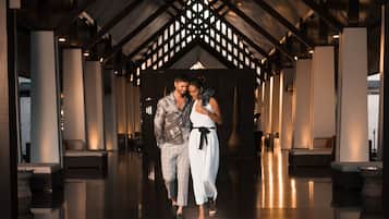 A couple walking through a modern lobby with a high ceiling and geometric ceiling design.