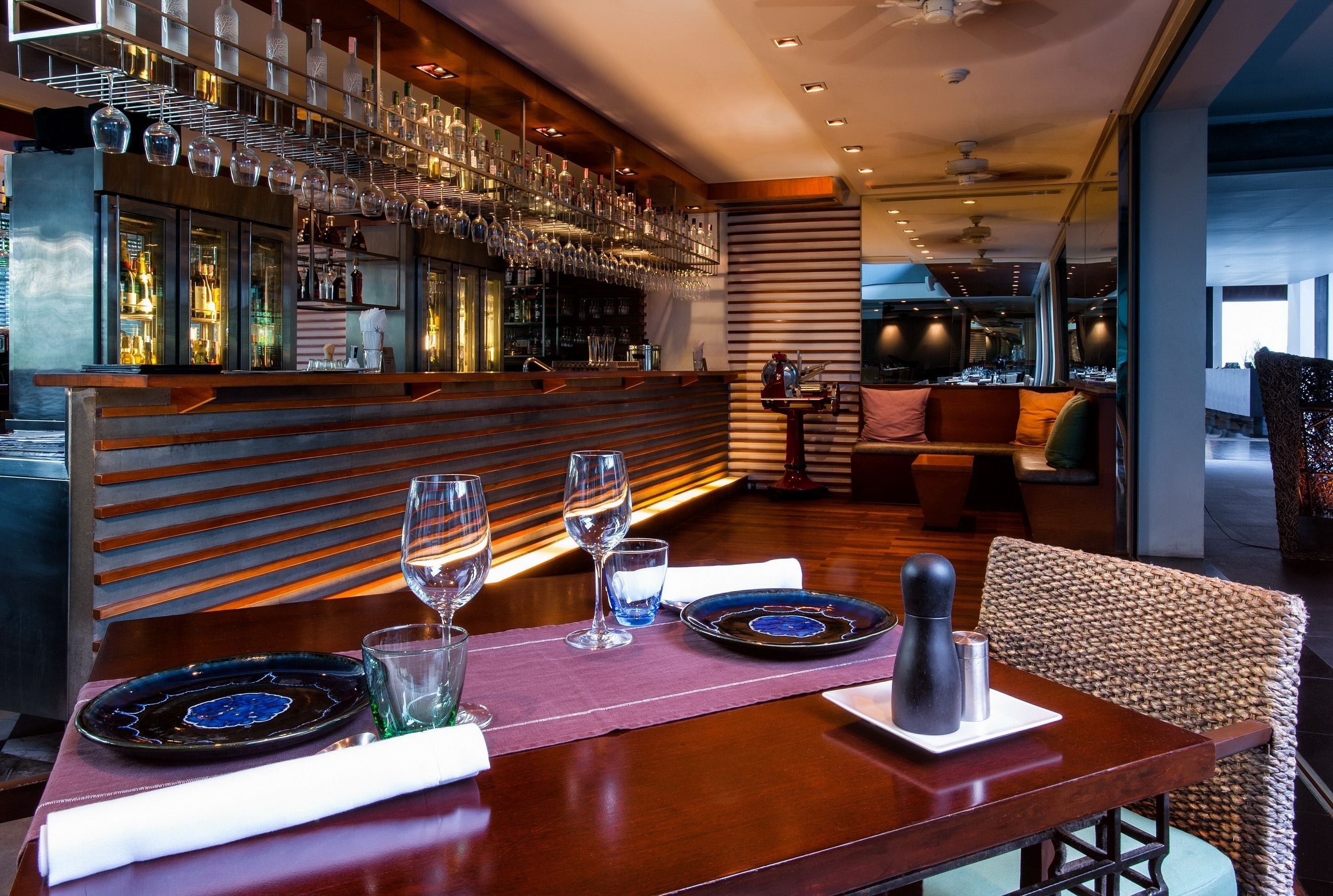 A restaurant with a bar area, wooden furniture, and a modern interior design.