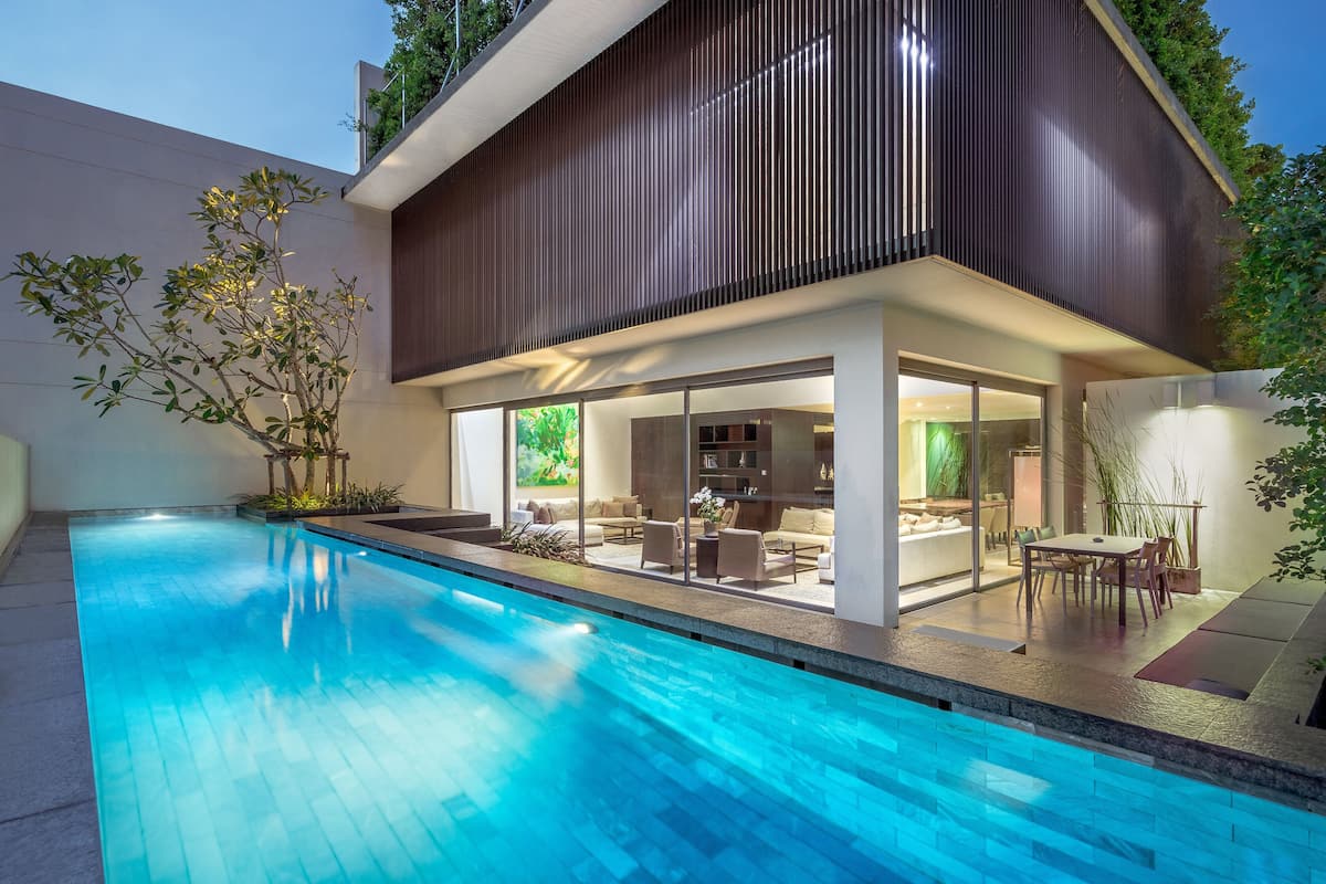Une maison moderne dotée d’une piscine, de grandes fenêtres et d’un espace patio.