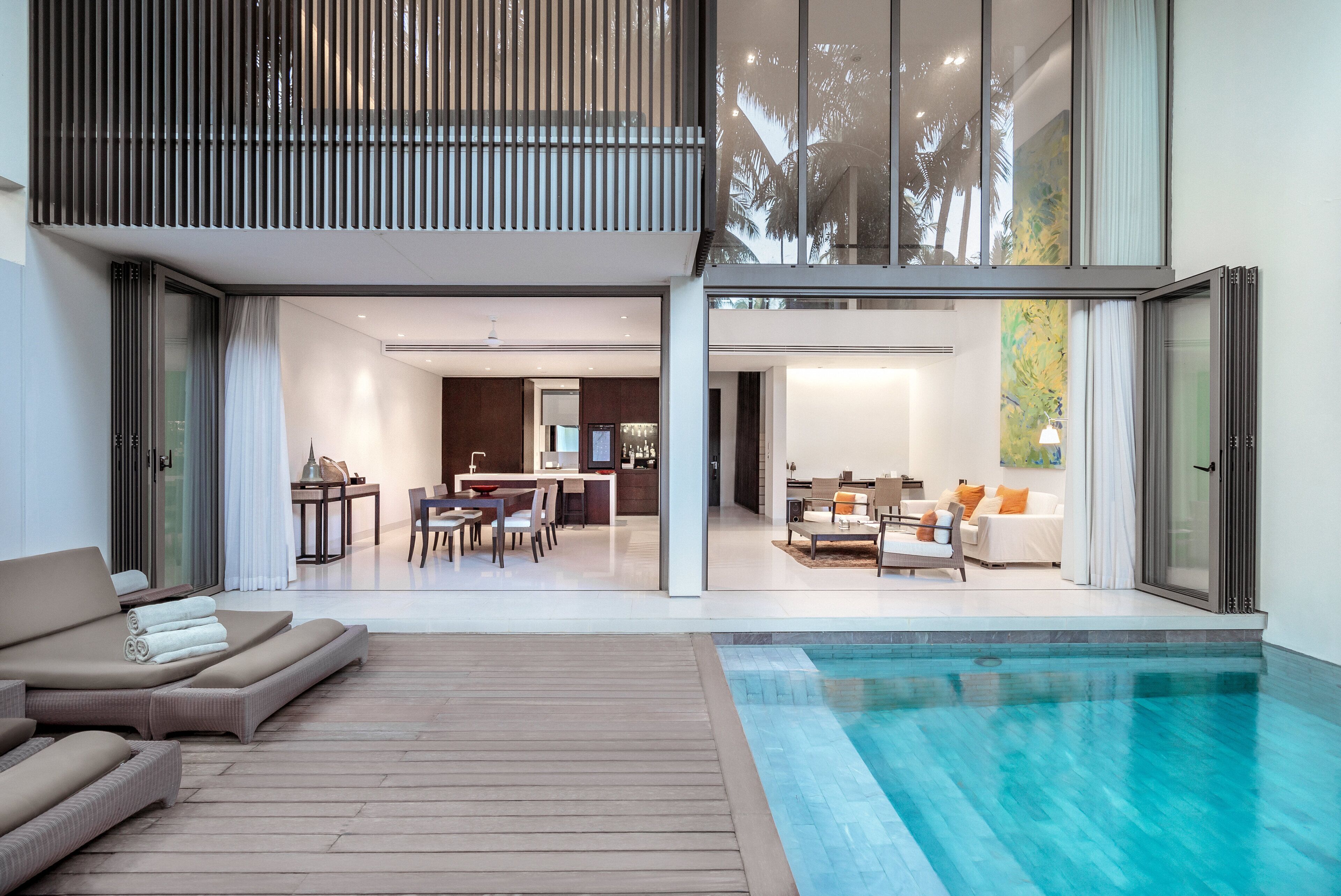 Een modern huis met een zwembad, een eetgedeelte en een woonkamer met een bank en een televisie.