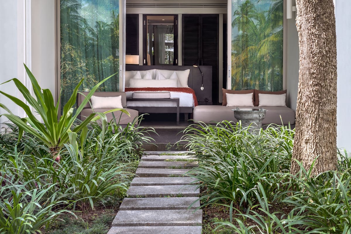 Une chambre avec un lit, un canapé et une grande fenêtre donnant sur une forêt tropicale.