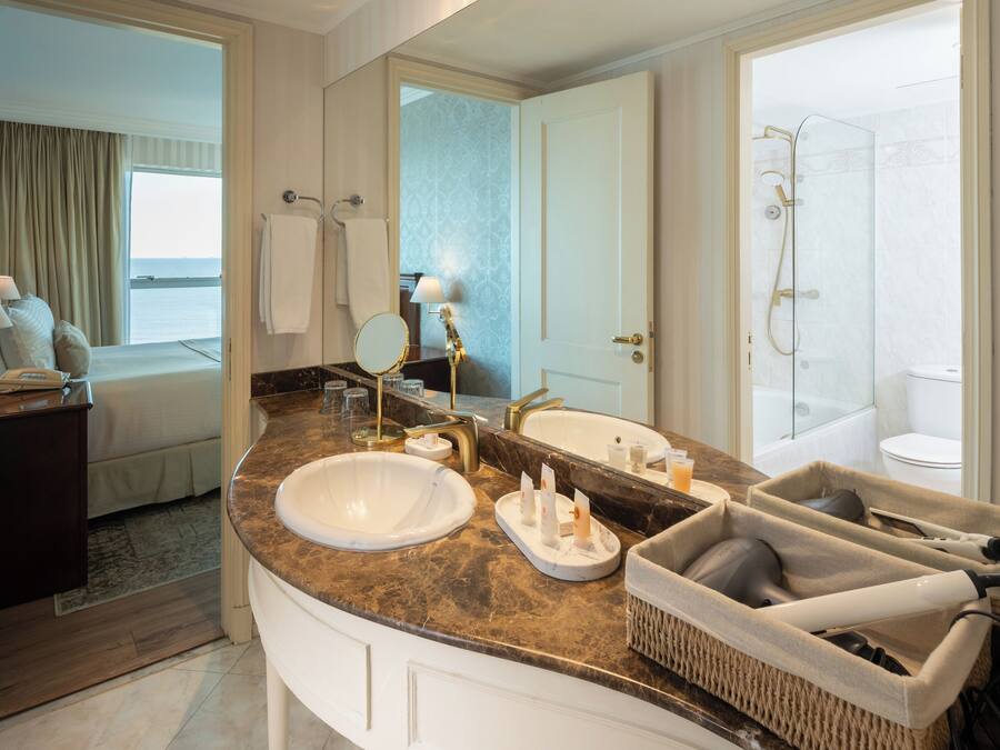 Un baño moderno con un espejo grande, dos lavamanos, una bañera y una ducha.