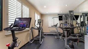 Un gimnasio con cintas de correr, elípticas y equipo de pesas.