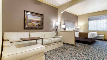A hotel room with a sofa, a bed, a desk, and a large window.