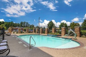 Una piscina al aire libre, sombrillas, sillones reclinables de piscina