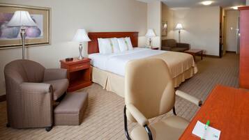 A hotel room with a bed, two bedside tables, a desk, a chair, and a lamp.