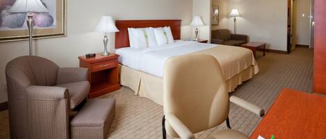 A hotel room with a bed, two bedside tables, a desk, a chair, and a lamp.