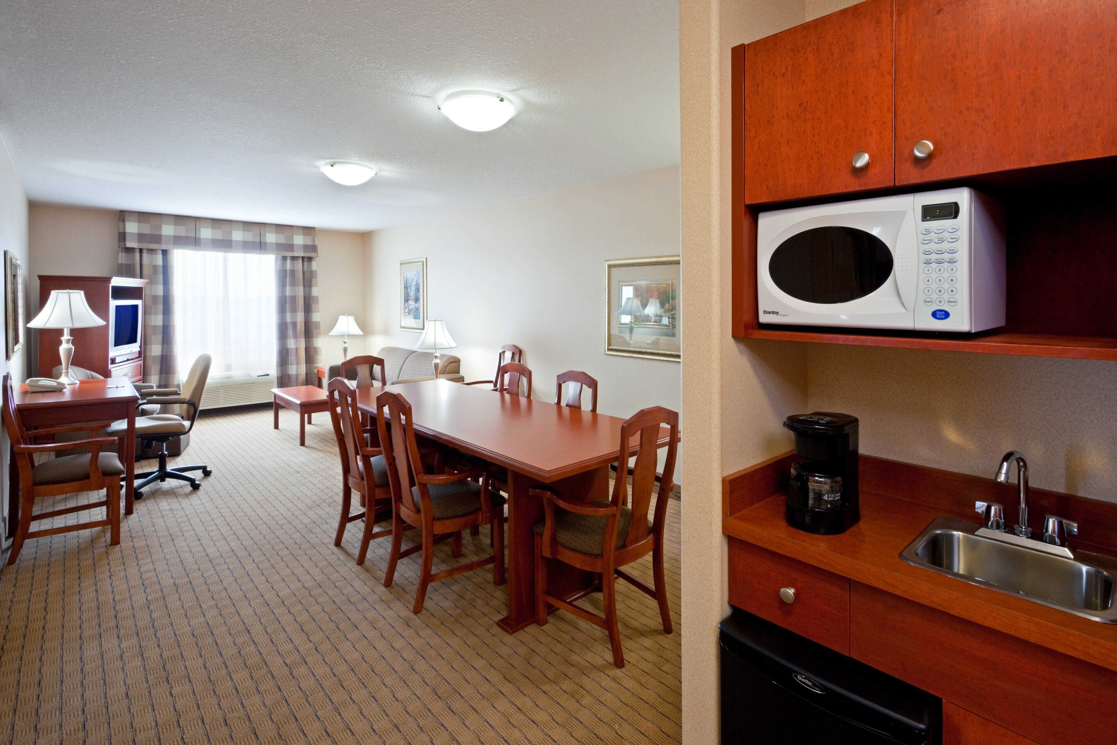 A hotel room with a dining area, a microwave, a coffee maker, and a sink.