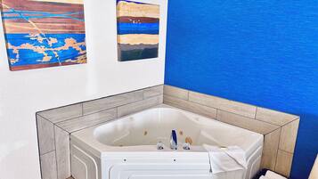Un baño moderno con una bañera independiente, paredes con azulejos y obras de arte.