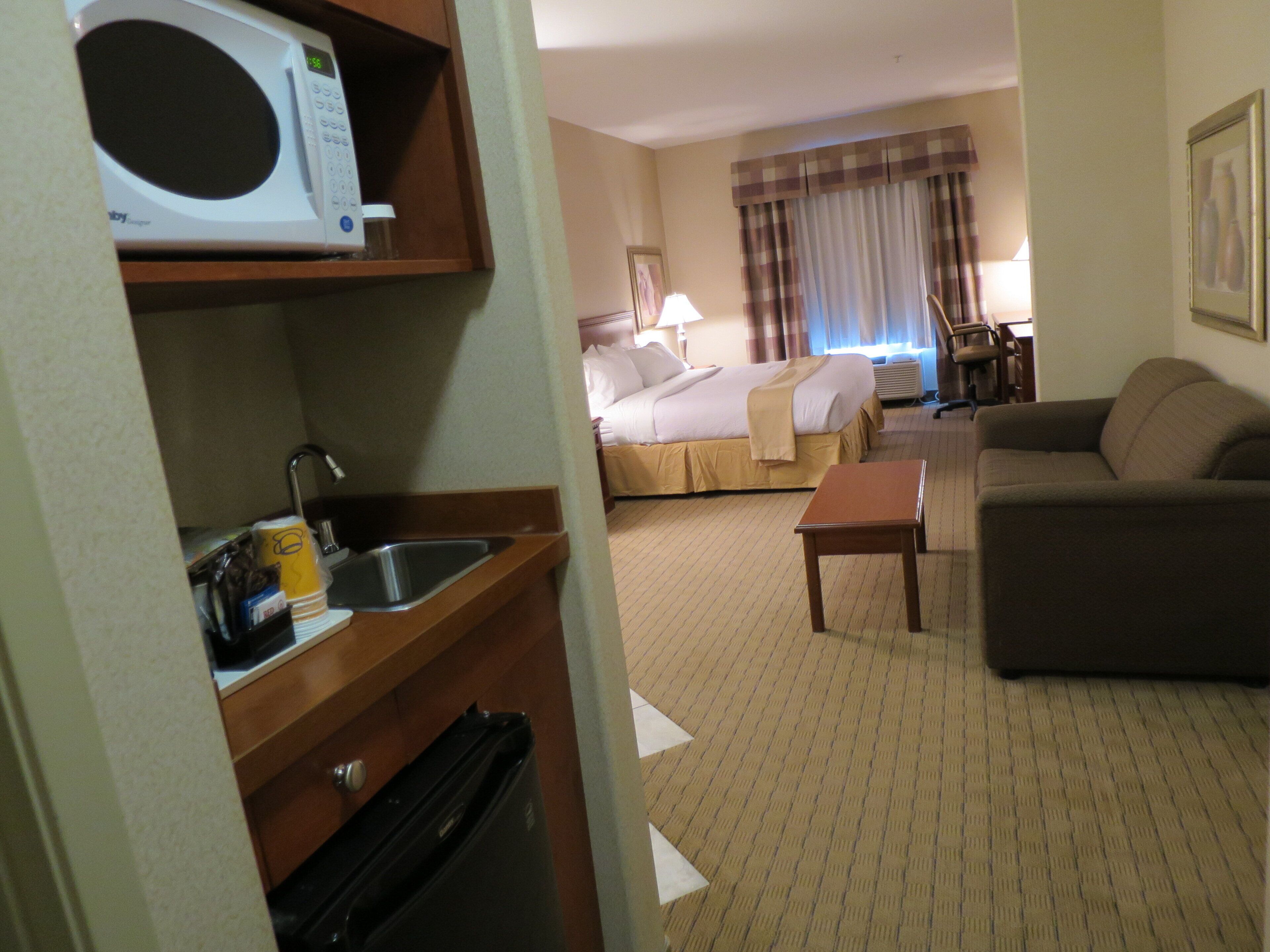 Une chambre d’hôtel équipée d’un lit, d’un canapé, d’une petite table, d’un four à micro-ondes et d’un évier.
