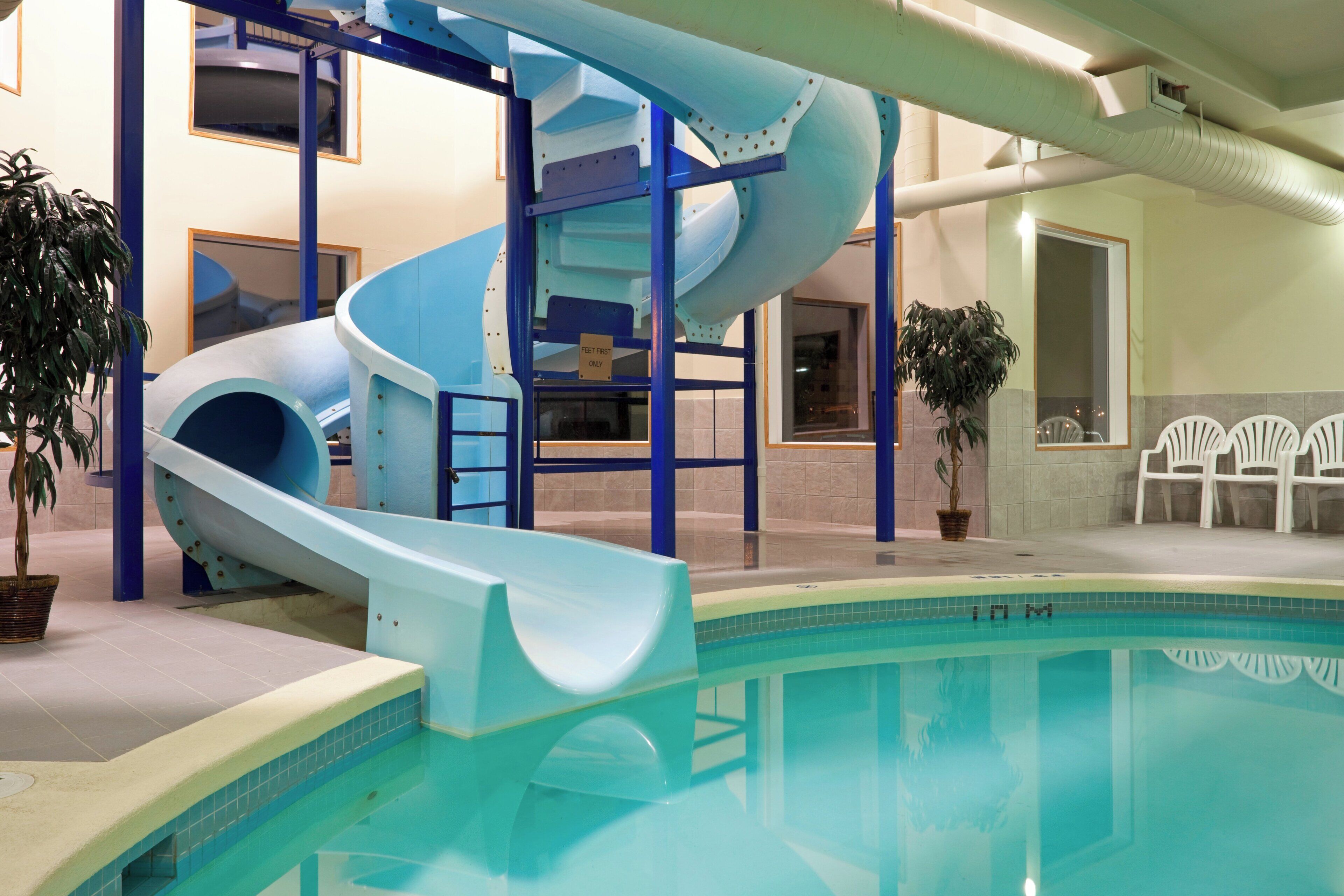 An indoor swimming pool with a blue slide and a staircase.