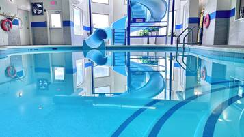 Une piscine avec un toboggan bleu en forme de spirale, une eau claire et du matériel de sécurité.