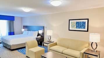 A hotel room with a bed, two armchairs, a sofa, a coffee table, and a side table with lamps.