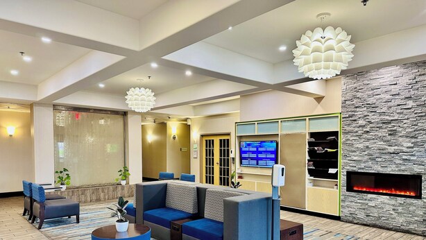 A modern lobby with a sectional sofa, a coffee table, and a fireplace. - Holiday Inn Hotel & Suites Regina by IHG (Regina)