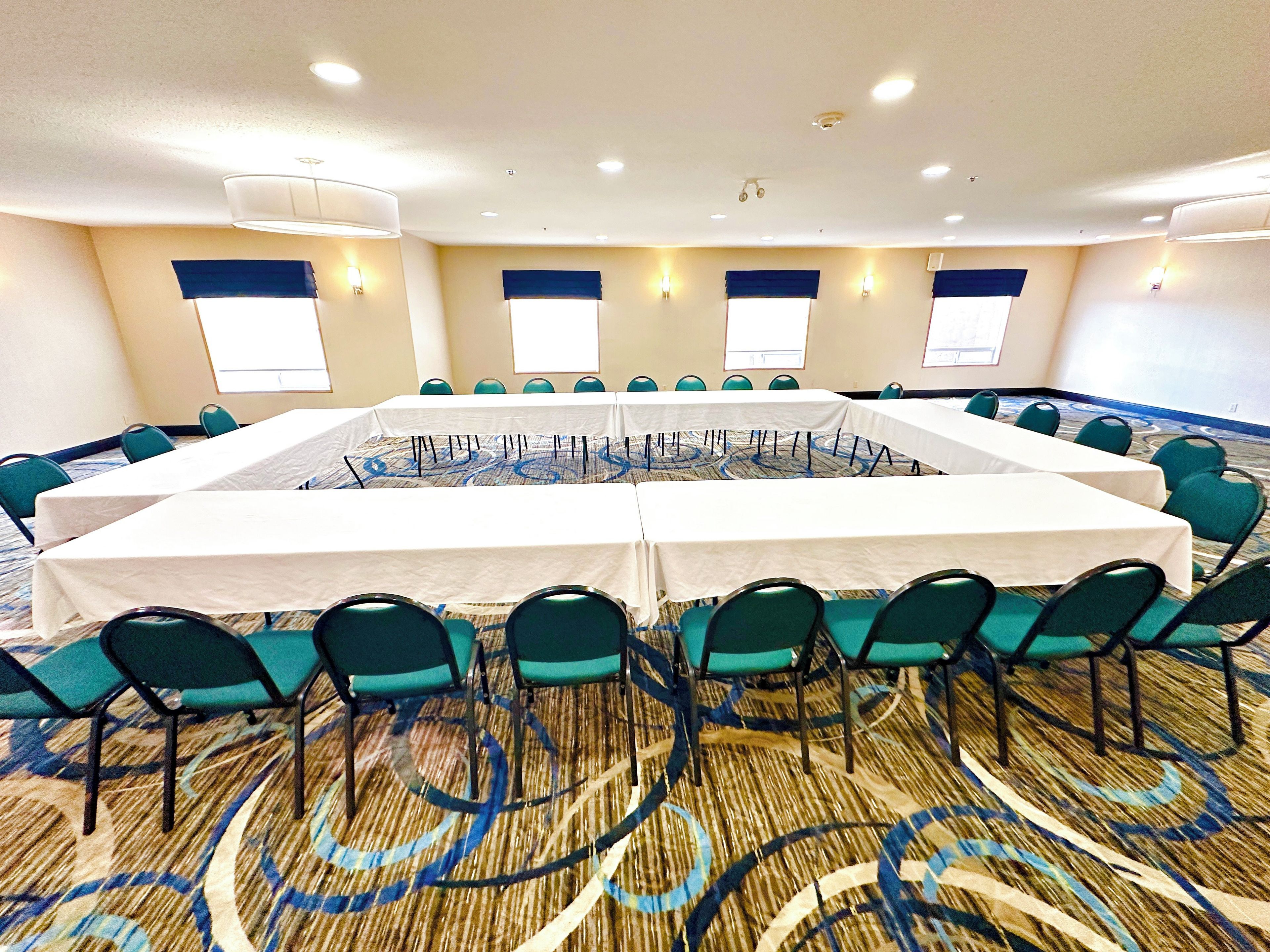 A conference room with a long table, chairs, and carpeted floor.