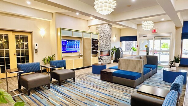 A modern lobby with seating areas, a fireplace, and a digital display. - Holiday Inn Hotel & Suites Regina by IHG (Regina)