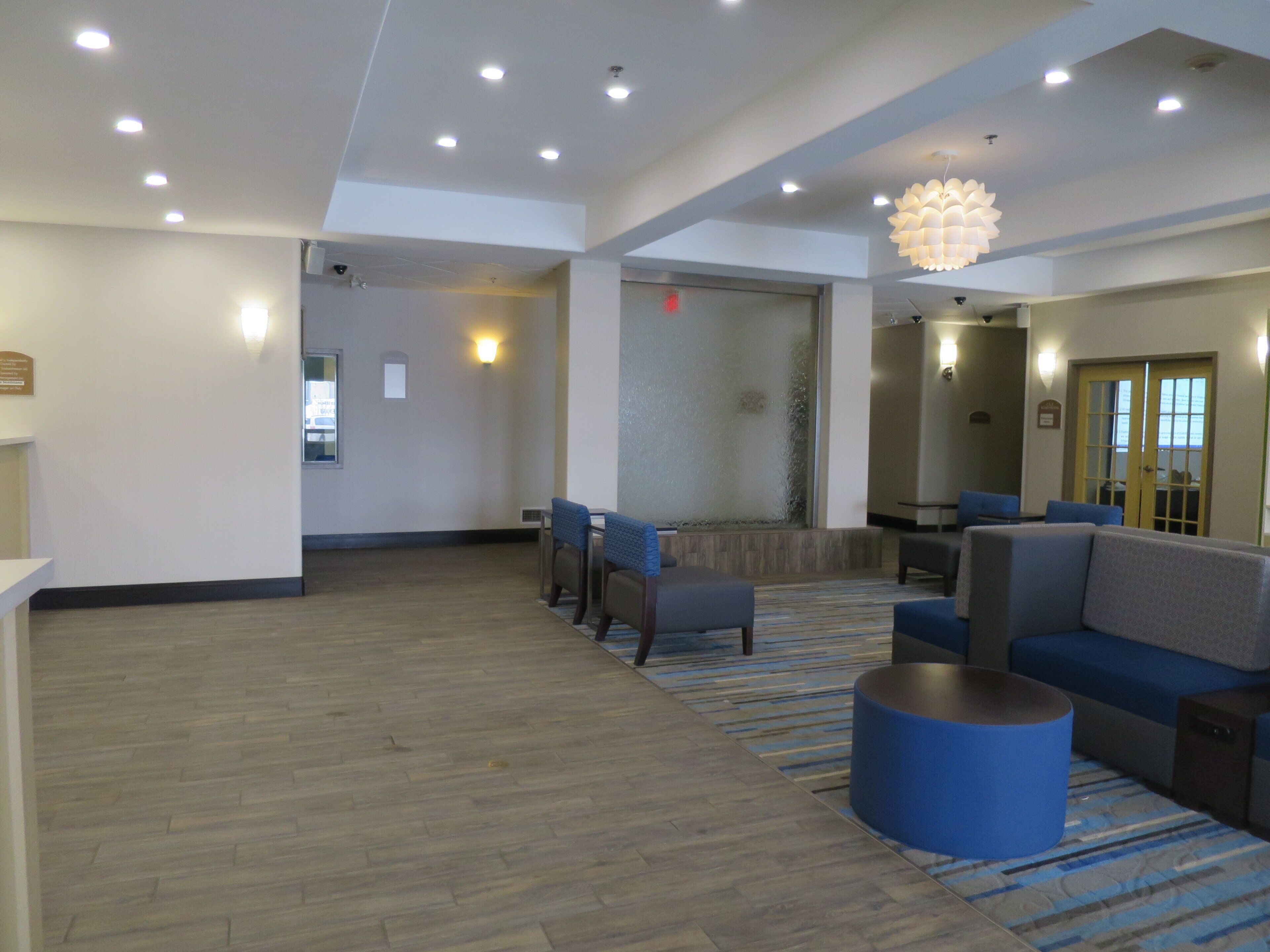 A hotel lobby with a seating area, a reception desk, and a large chandelier.