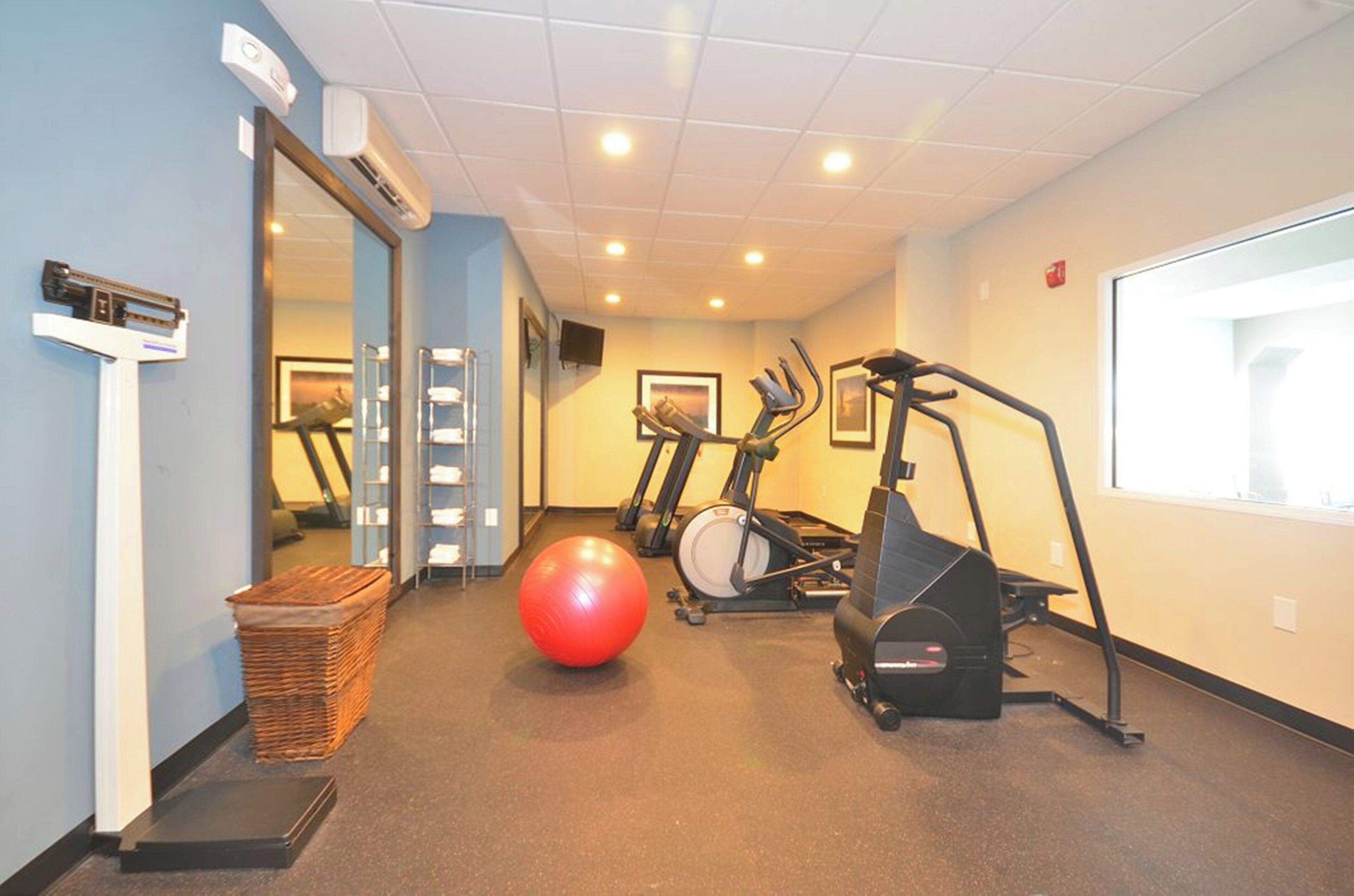 A fitness room with exercise equipment, a large red exercise ball, and a mirror.