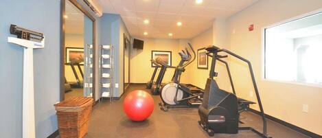 A fitness room with exercise equipment, a large red exercise ball, and a mirror.