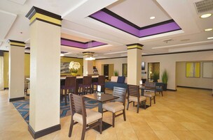 Un hall de hotel con un área de estar central, varias mesas y sillas.