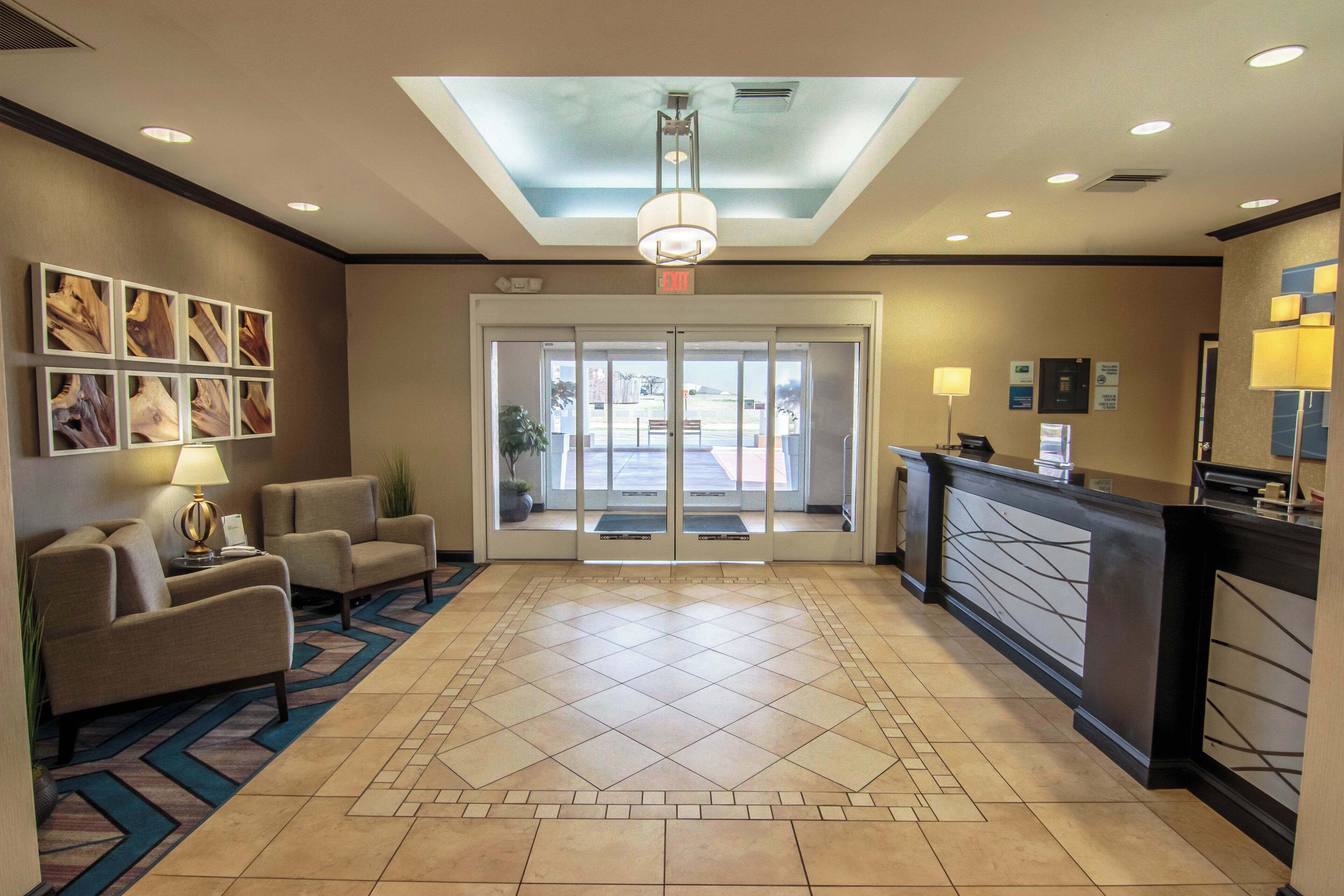 A hotel lobby with a reception desk, seating area, and a patterned floor.