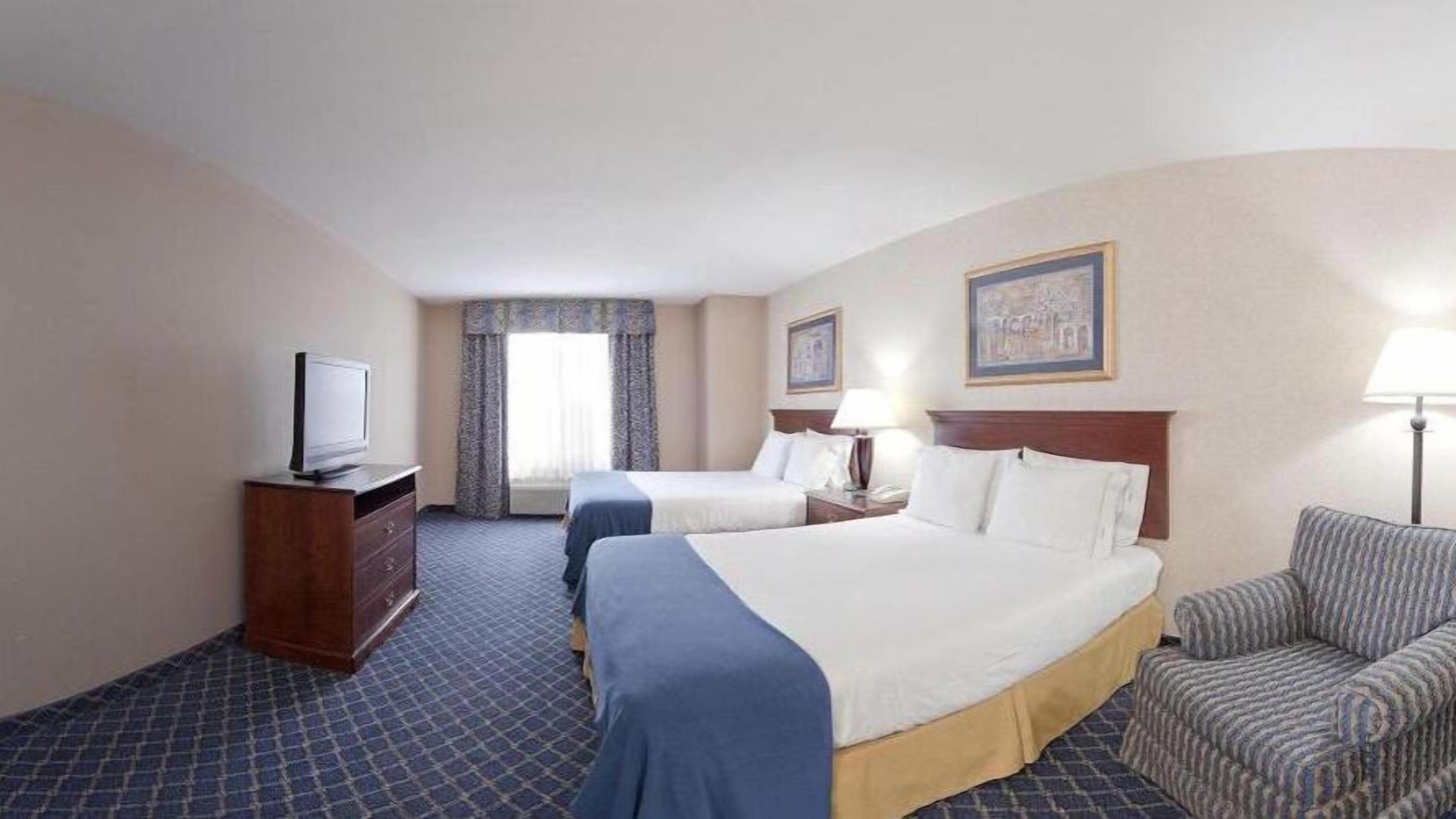 Une chambre d’hôtel avec deux lits, une télévision, un bureau et une chaise.