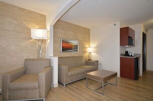 Una sala de estar moderna con un sofá, sillones, una mesa de centro y un cuadro en la pared.