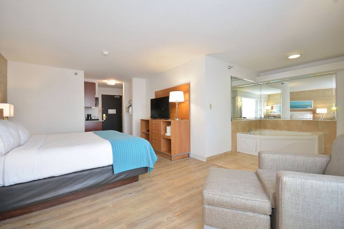 Ein Hotelzimmer mit Bett, Schreibtisch, Stuhl, Sofa, Bad und Fernseher.