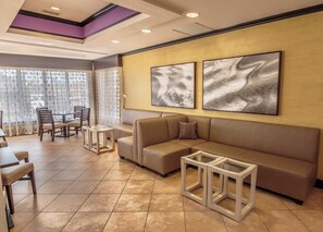 A modern living room with a sectional sofa, a coffee table, and a dining area with chairs and a table. - Holiday Inn Express & Suites Farmington by IHG (Farmington)