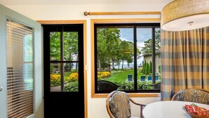 Une pièce avec une porte donnant sur un jardin, une fenêtre avec vue sur le jardin et une table avec des chaises.