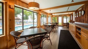 Un vaste espace intérieur doté de grandes fenêtres, de murs en bois et offrant une vue sur la piscine.