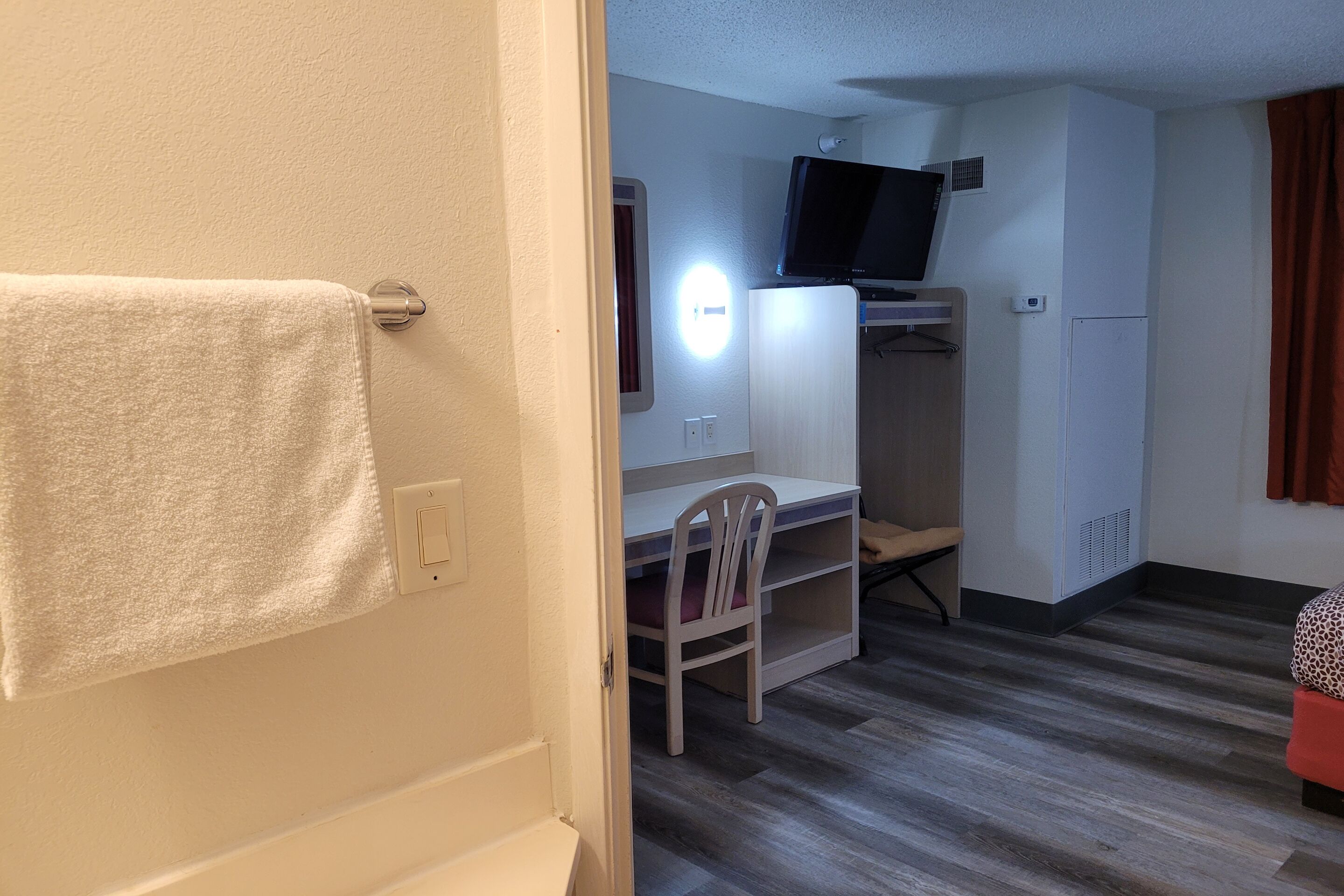 Una habitación de hotel con cama, escritorio con silla, televisión y armario.