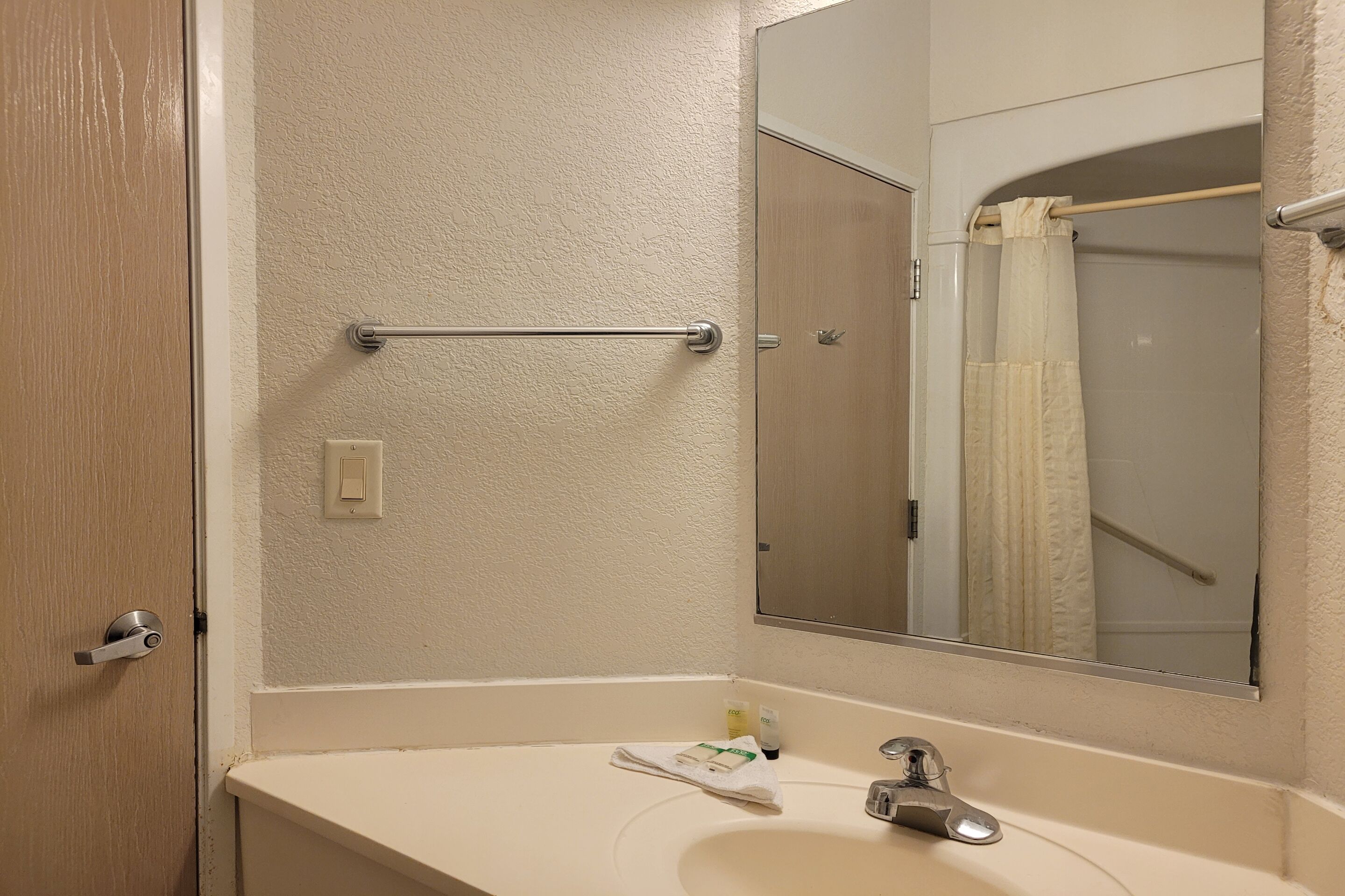 A bathroom with a white sink, a mirror, a towel, and a shower curtain.